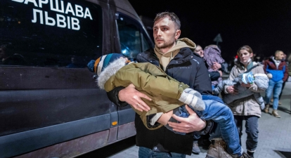 Волонтер несе дитину громадян України, які прибувають на автобусах до Пшемсила, східна Польща, від пішохідного прикордонного переходу Медика, пізно ввечері 25 лютого 2022 року /Getty Images