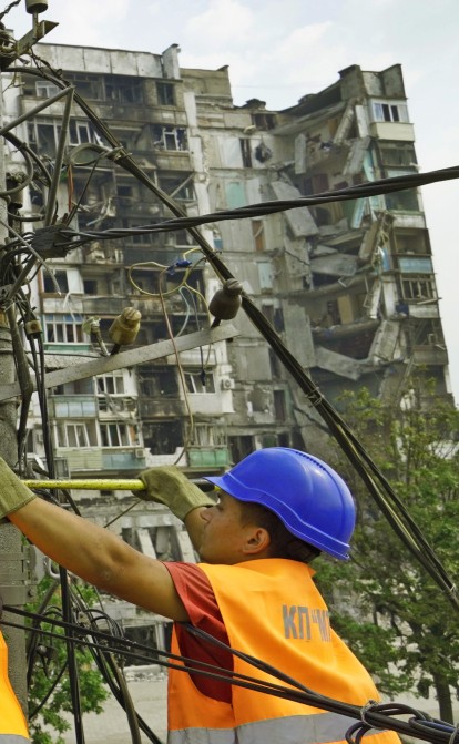 Робітники в Маріуполі лагодять розбиті російськими ракетами лінії електропередач, 1 серпня 2022 року. /Getty Images