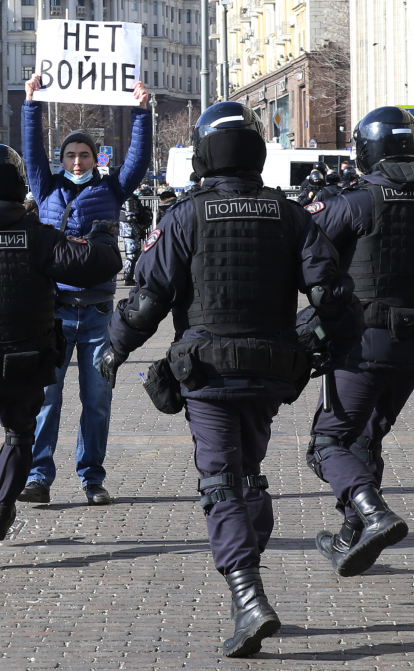 Російські поліцейські біжать затримувати чоловіка з плакатом «Ні війні» під час протесту біля Кремля 13-го березня. /Getty Images