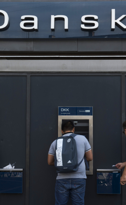 Люди снимают наличные в банкоматах Danske Bank в Копенгагене (Дания) /Getty Images